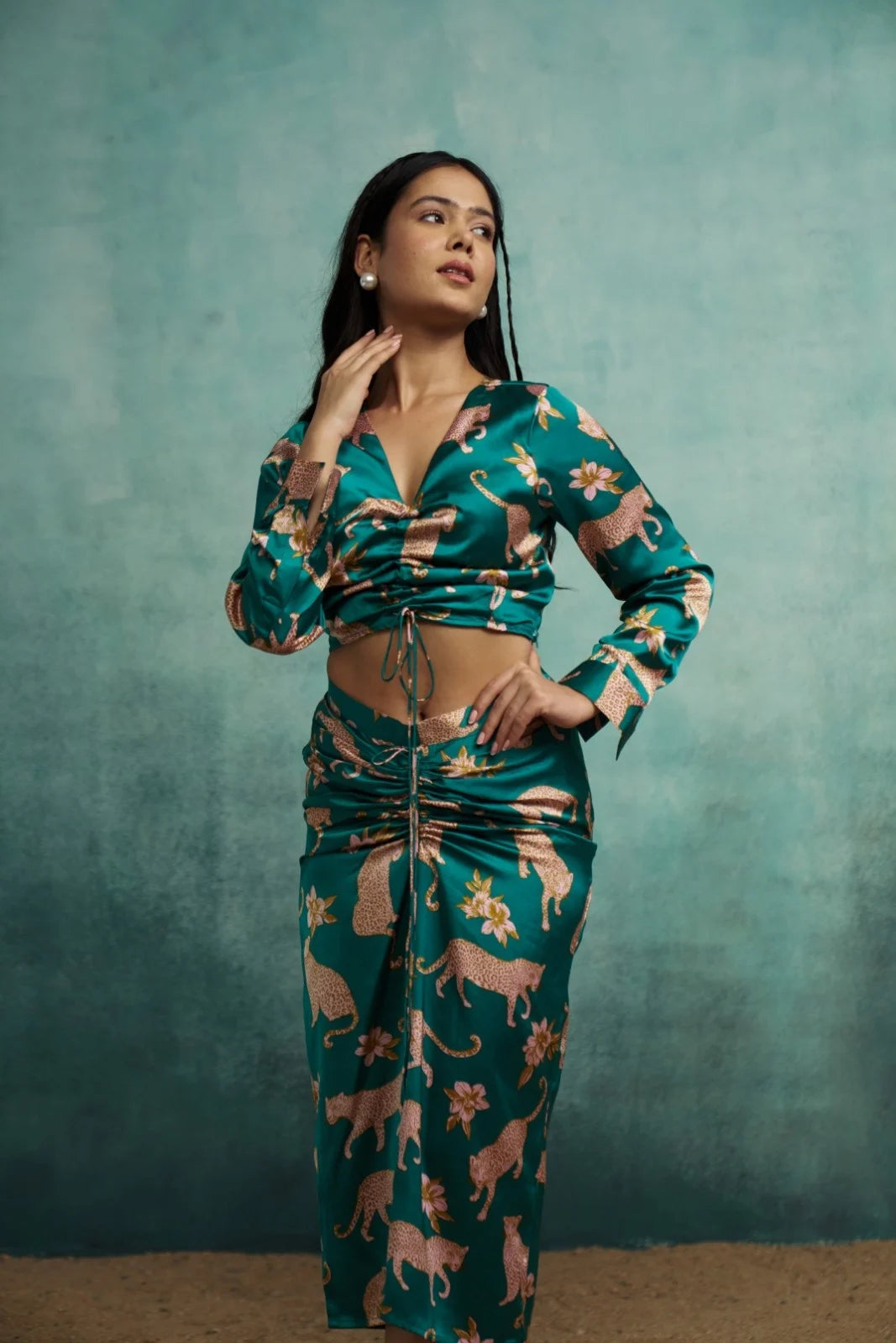 Woman wearing a green patterned outfit against a teal background