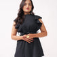 Woman wearing a black outfit with ruffled details on a white background
