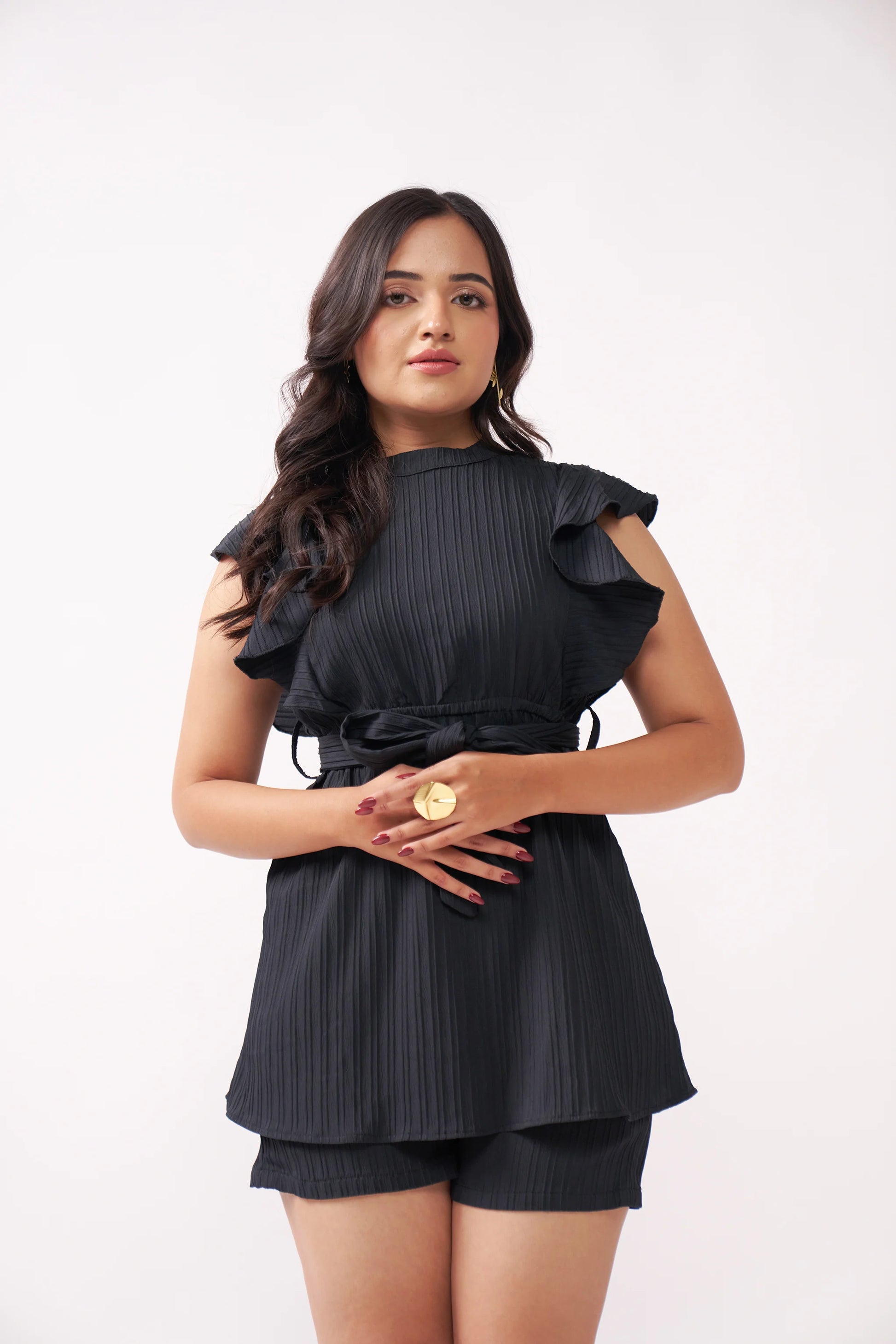Woman wearing a black outfit with ruffled details on a white background