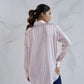 Woman wearing a light pink and white striped shirt against a white background