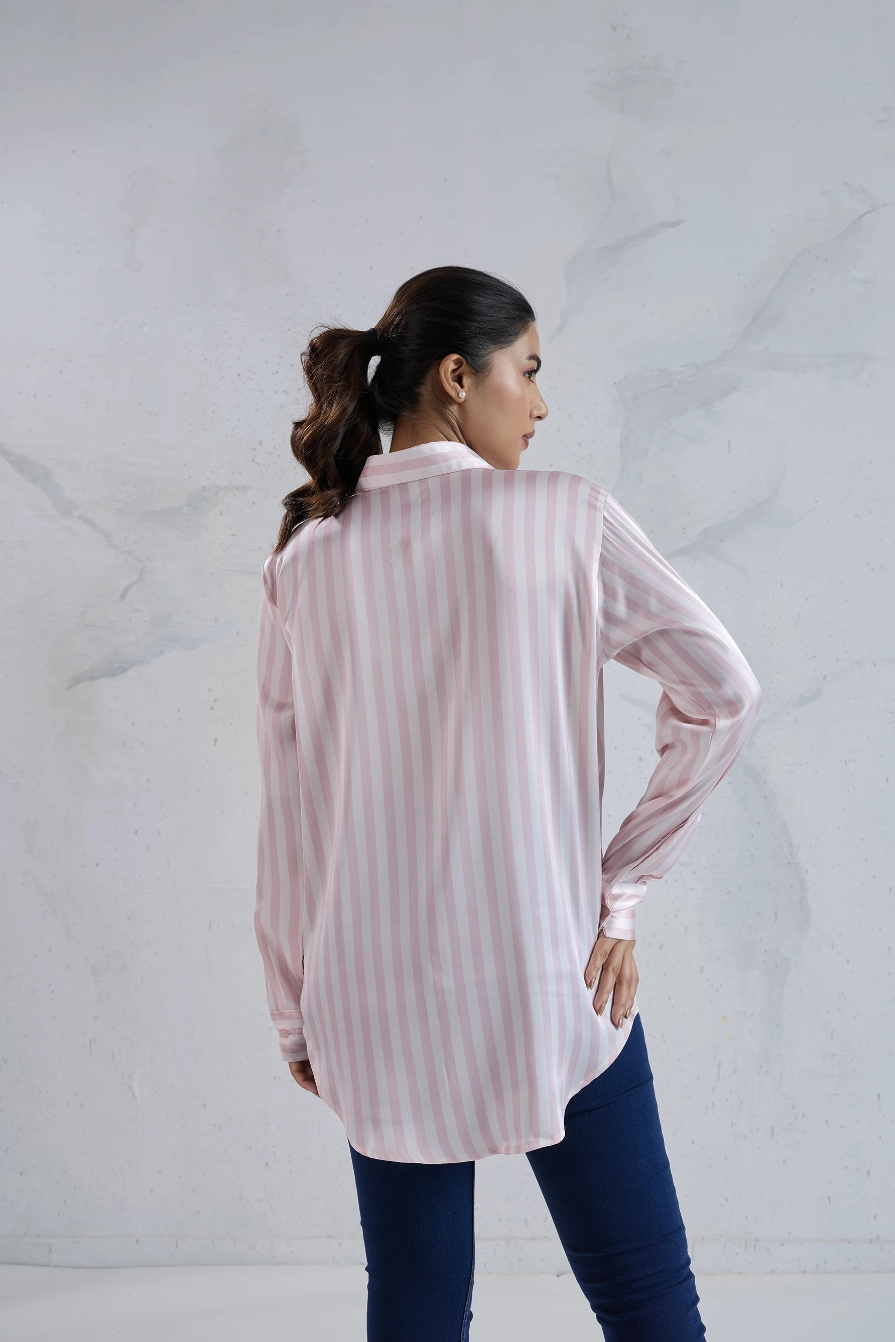 Woman wearing a light pink and white striped shirt against a white background