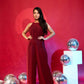 Woman in a red jumpsuit posing against a red background with silver balloons.