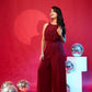 Woman in a red jumpsuit standing against a red background with decorative spheres.