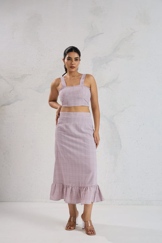 Woman wearing a matching pink top and skirt set against a white background