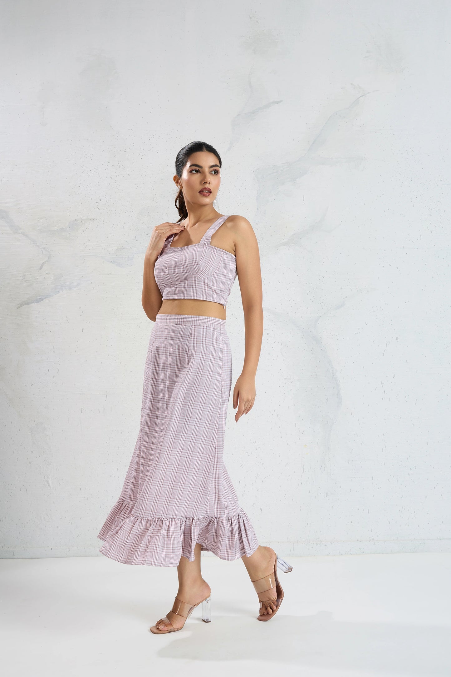 Woman wearing a light purple one-shoulder top and skirt on a white background