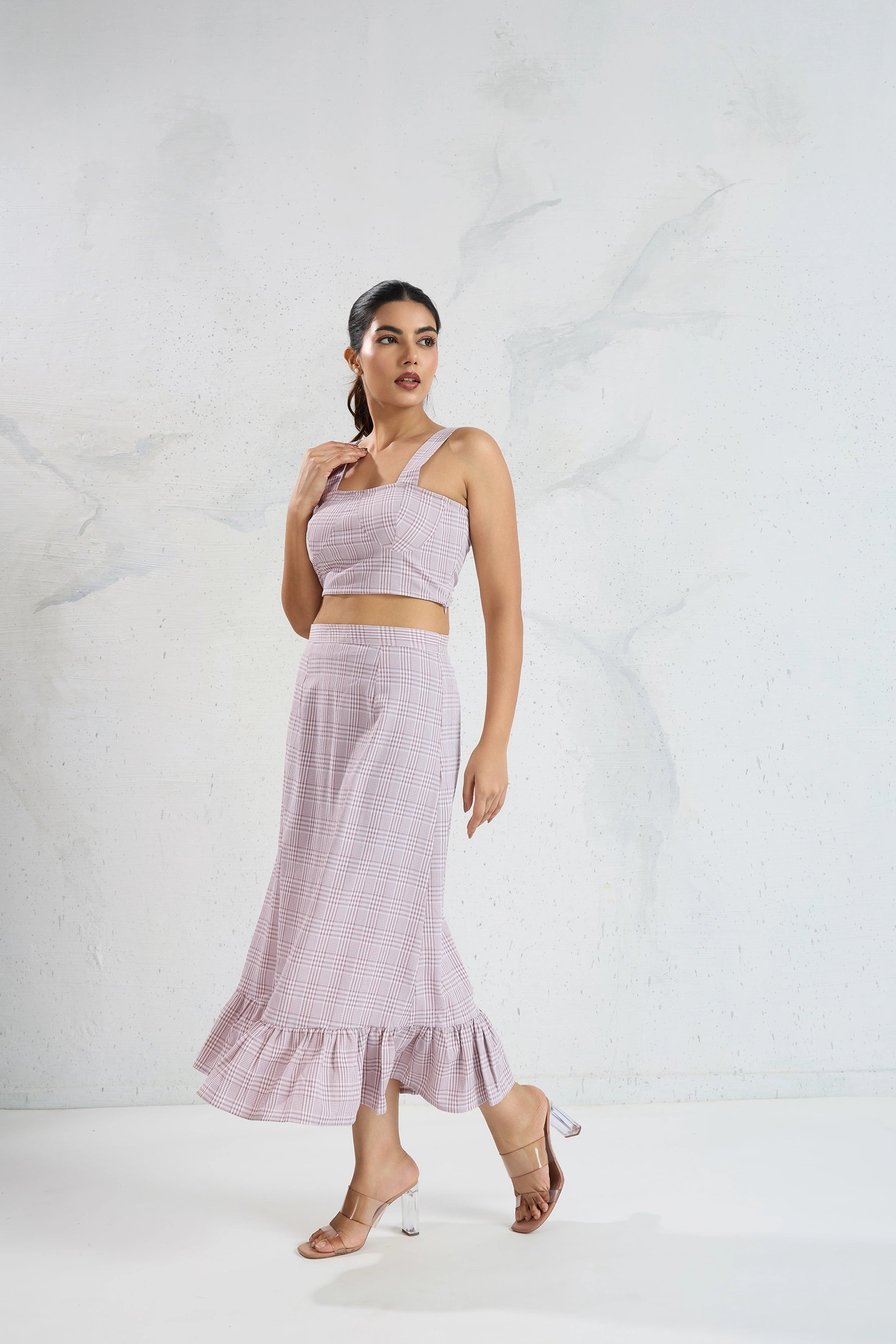 Woman wearing a light purple one-shoulder top and skirt on a white background