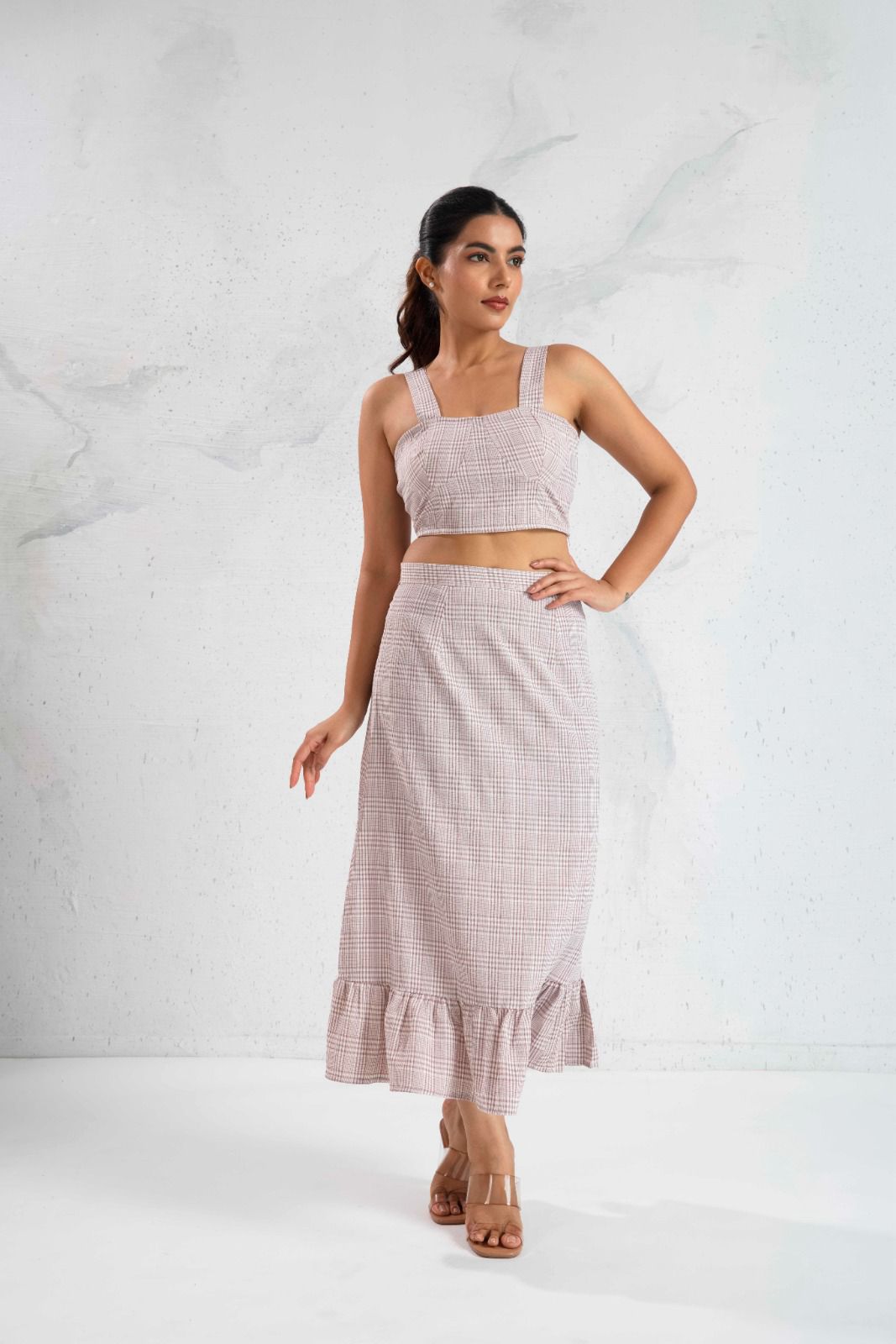 Woman wearing a matching set of top and skirt with ruffled hem on a white background