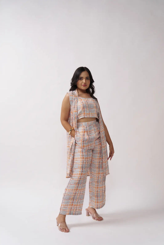 A female model wearing a sleeveless top and matching pants with a plaid pattern in multicolor with grey and orange shades.
