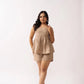 A woman posing in a beige linen co-ord set consisting of a sleeveless top and shorts.