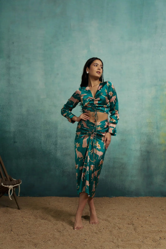 Woman wearing a patterned outfit against a textured teal wall.