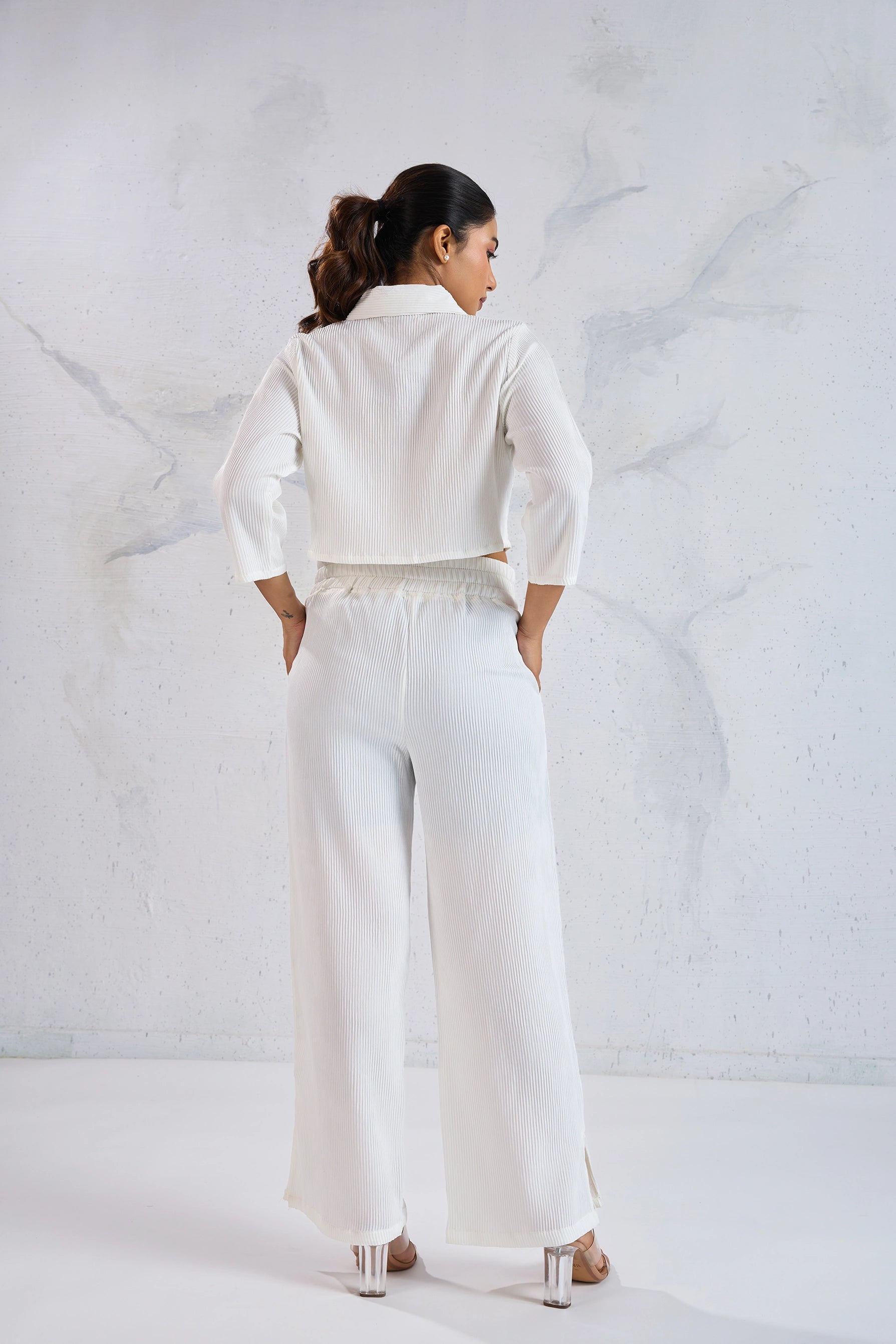 Person wearing a white outfit against a white marble wall