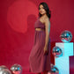 Woman in a pink dress standing against a red background with disco balls.
