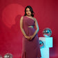 Woman in a pink dress standing against a red background with disco balls.