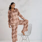Woman in a patterned outfit sitting on a wire chair against a white background