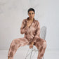 Woman in a patterned outfit sitting on a chair against a white background