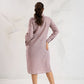 Woman wearing a light pink dress standing against a white background