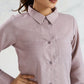 Woman wearing a light purple button-up shirt against a plain background