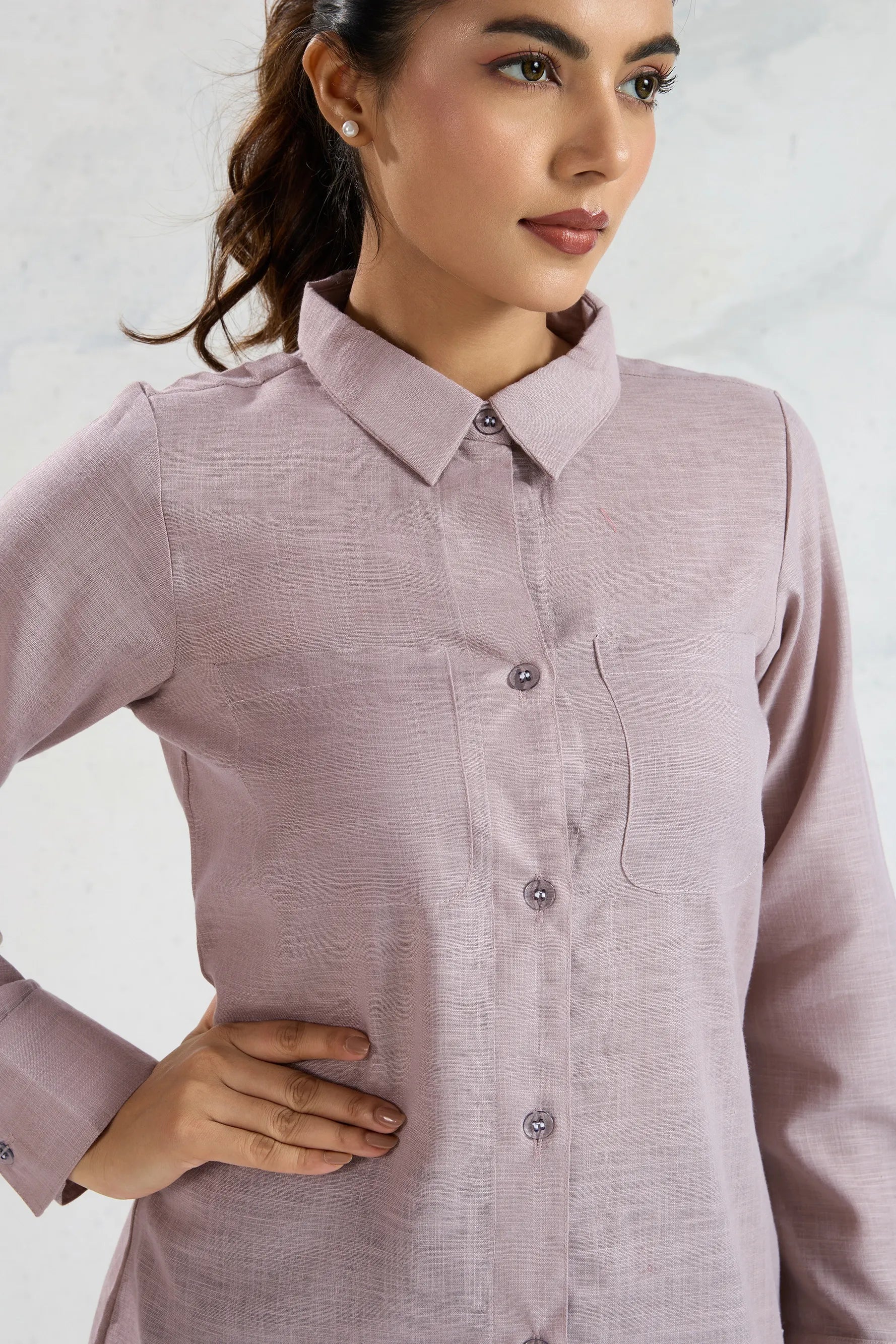 Woman wearing a light purple button-up shirt against a plain background