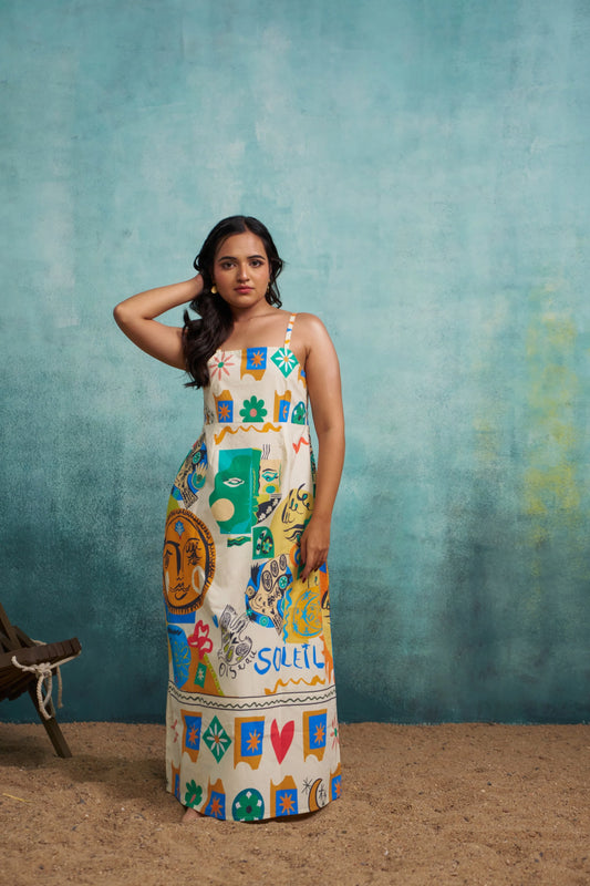 Woman wearing a colorful patterned dress against a textured blue wall.