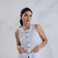 Woman wearing a white sleeveless knitted top against a light gray background