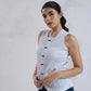Woman wearing a sleeveless white top with black buttons against a light gray background