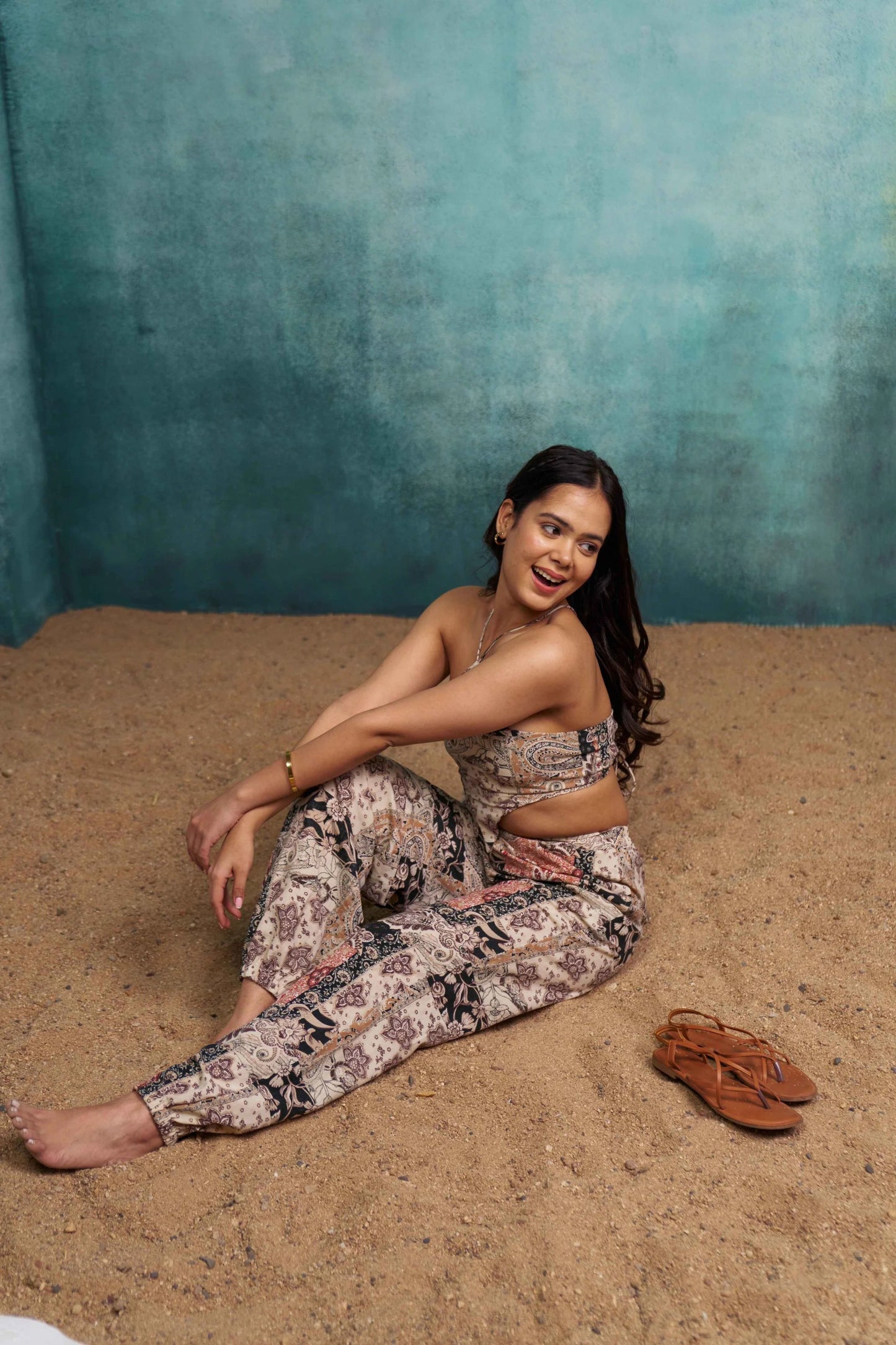 Woman sitting on sand against a textured blue wall