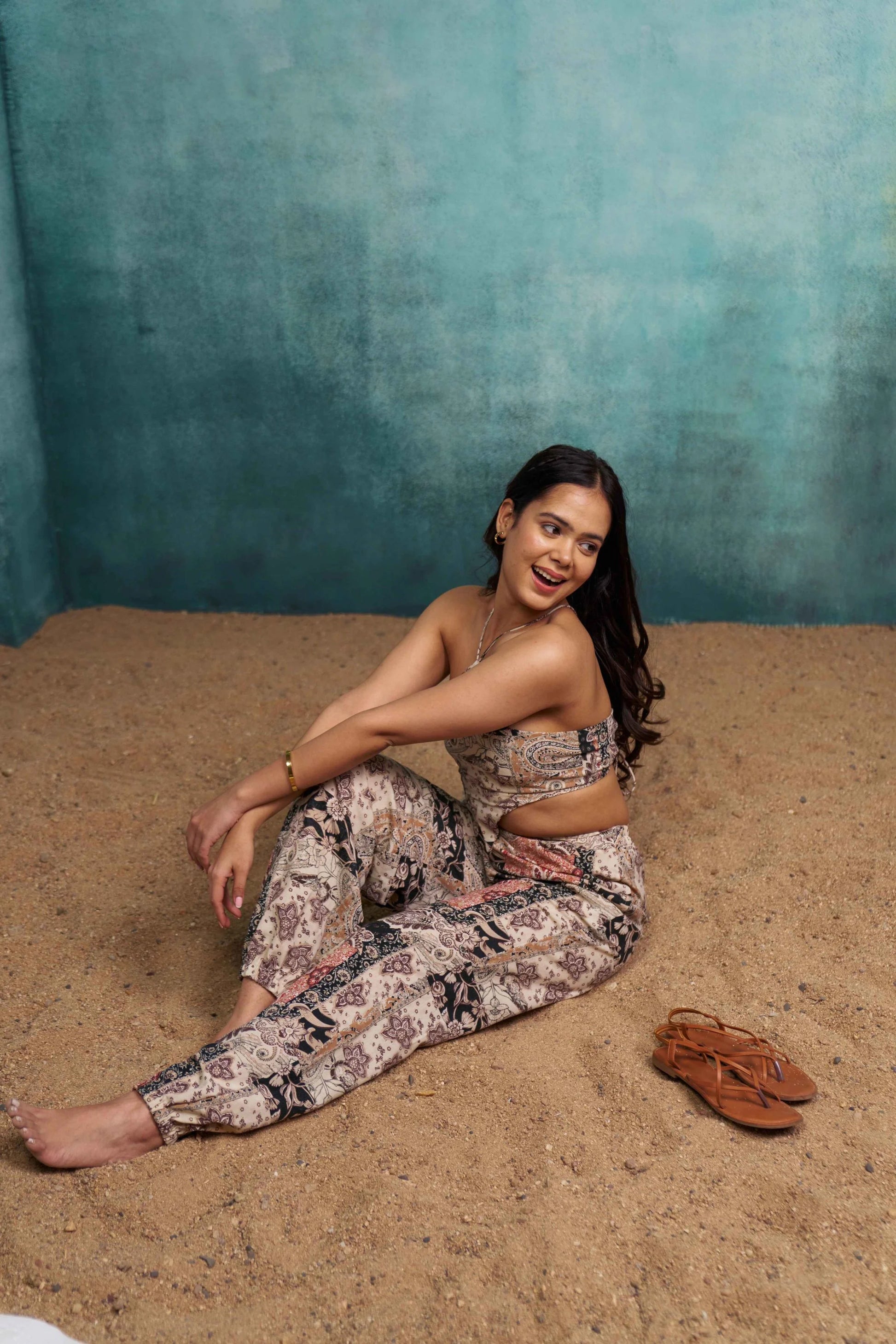 Woman sitting on sand against a textured blue wall